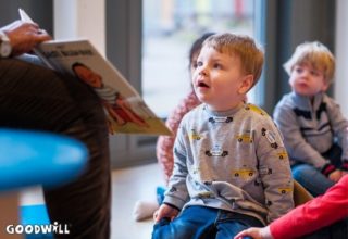 Een kindje kijkt met grote ogen naar Gerda Havertong die een boek voorleest-Goodwill.nl