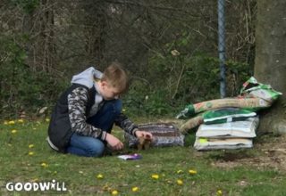 Foto van een jongen bij zakken aarde en mest voor de moestuin-Goodwill.nl