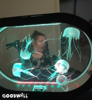 Gehandicapt kindje kijkt ontspannen naar een aquarium met verlichte kwalletjes